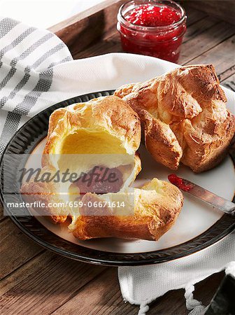 Two Popovers on a Plate; One Split Open with Strawberry Jam