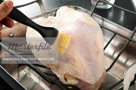 Brushing Butter on a Turkey Breast in the Oven for Roasting Brushing Butter on a Turkey Breast in the Oven for Roasting