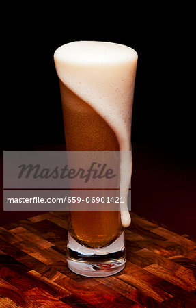 Glass Mug of Beer with Foam Spilling Over Glass Mug of Beer with Foam Spilling Over