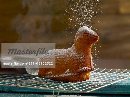 Easter lamb (cake) on cooling rack being sprinkled with powdered sugar