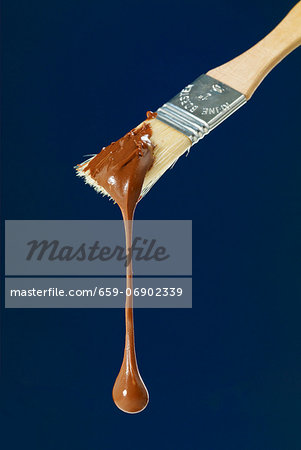 Melted chocolate dripping from a pastry brush