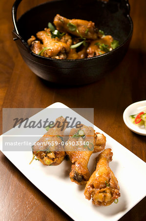 Asian Style Chicken Drumettes on a Platter; Chicken in Bowl in Background