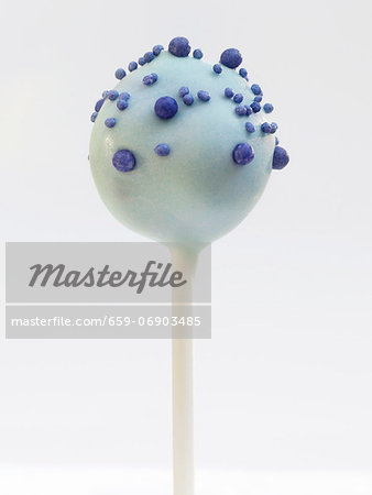 A cake pop with blue glaze and sugar pearls
