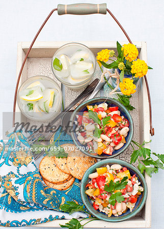 Two Bowls of Cherry Tomato and Bean Salad with Feta Cheese; Crackers and Drinks on a Tray