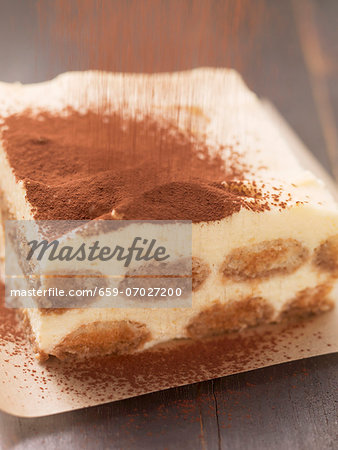 Tiramisu being sprinkled with cocoa powder