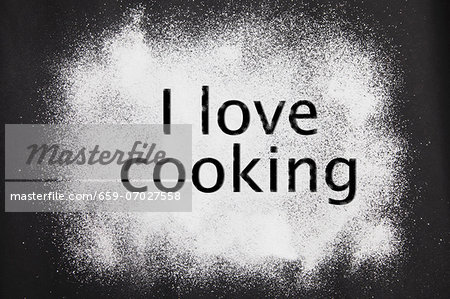 'I love cooking' etched in icing sugar on a black background
