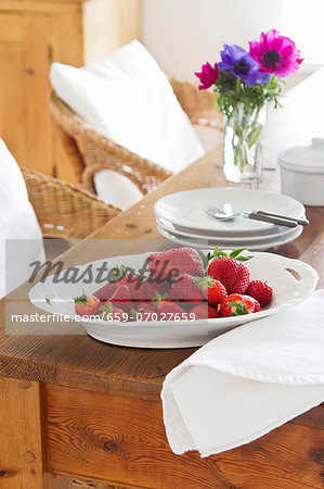 Fresh strawberries in a white porcelain dish on a vintage wooden table