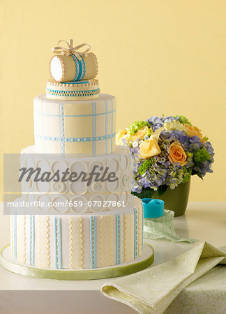 A four-tier wedding cake; behind it, a gorgeous bouquet of summer flowers