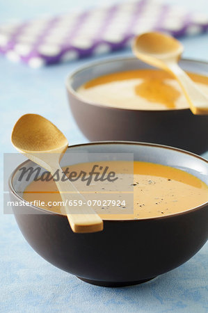 Squash soup in two bowls with wooden spoons