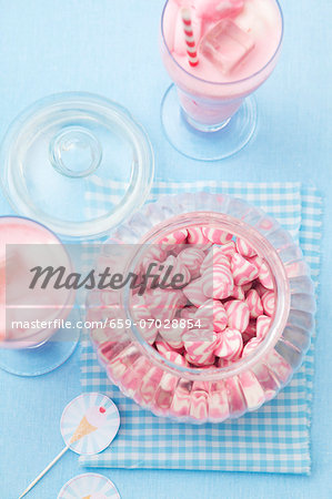 A jar of pink and white striped sweets, and a strawberry milkshake with marshmallows