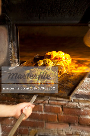 Freshly baked bread rolls on a baking tray in a wood-fired oven