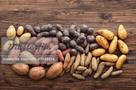 Assorted types of potato on a wooden surface