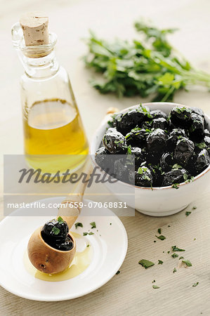 Black olives in a bowl, with parsley and olive oil
