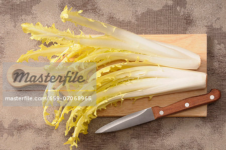 Dandelion leaves on a chopping board with a knife