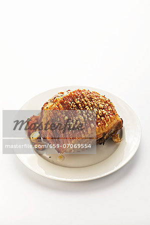 Whole roasted shoulder of pork on a white plate