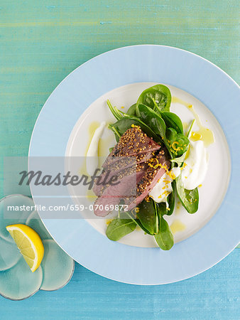 Marinated lamb fillet with mustard seeds on spinach leaves