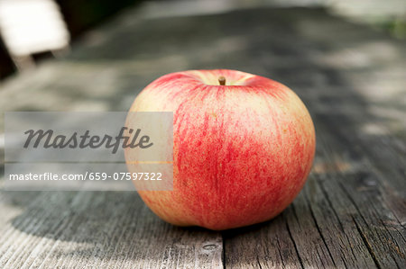 An apple on a wooden table in the garden An apple on a wooden table in the garden