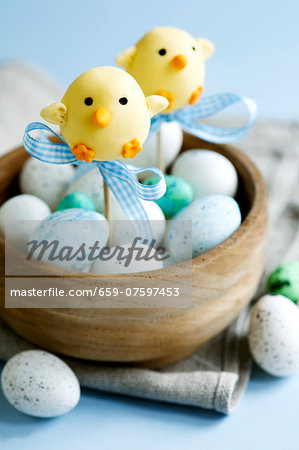 Easter chick cape pops and chocolate eggs in a wooden bowl Easter chick cape pops and chocolate eggs in a wooden bowl