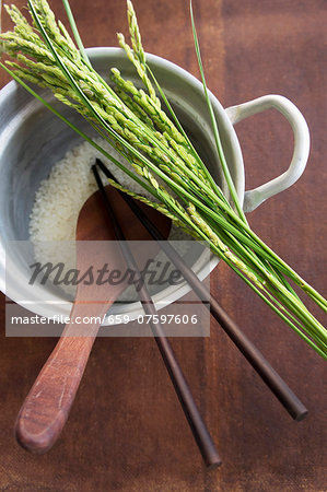 Rice and ears of rice, a wooden spoon and chopsticks in a pan of rice