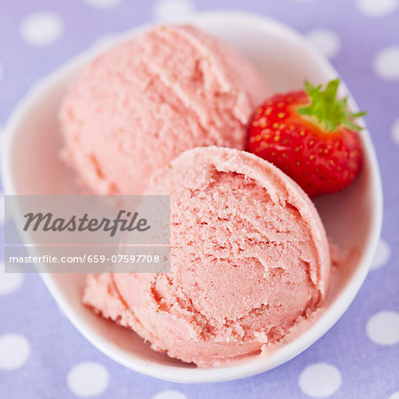 Two scoops of home-made strawberry ice cream with a fresh strawberry, viewed from above