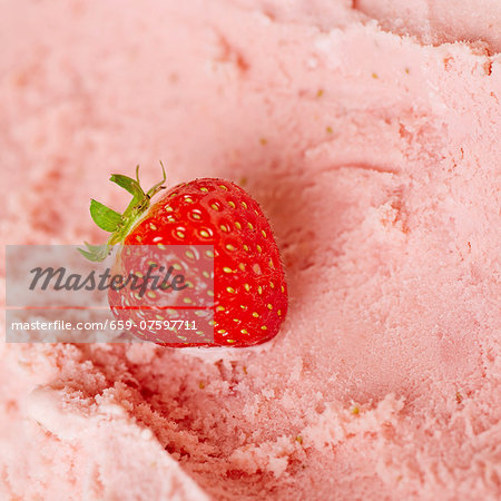 A fresh strawberry on fresh strawberry ice cream ready to be scooped