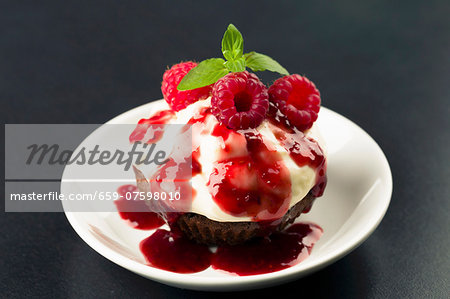 Cupcake with cream cheese topping and raspberry sauce