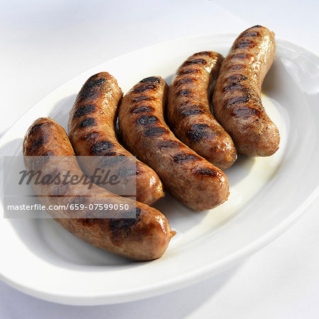 Five grilled Bratwurst on White Serving Platter on White Background