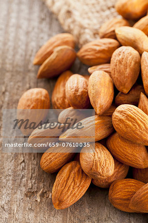 A pile of almonds on a wooden surface