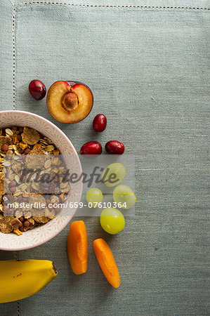 A bowl of muesli next to fresh fruit A bowl of muesli next to fresh fruit