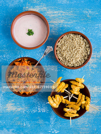 Chicken tandoori skewers with quinoa, carrot salad and raita in small bowls