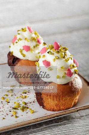 Marble cupcakes topped with white cream, pistachios and pink sugar Christmas trees