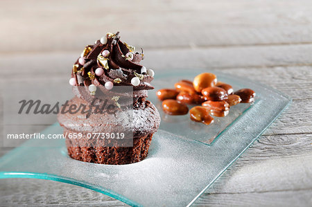 A chocolate cupcake decorated with sugar pearls and gold leaf