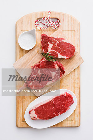 Various beef steaks and salt on a chopping board