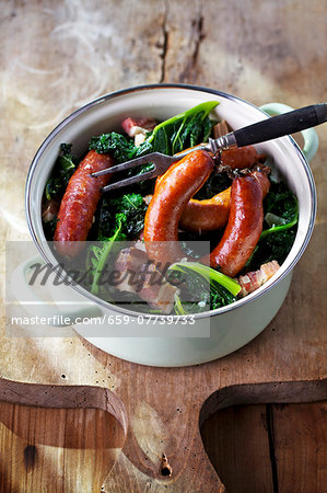 Green kale with Pinkel (smoked sausage from bacon, groats and spices) in a pot Green kale with Pinkel (smoked sausage from bacon, groats and spices) in a pot