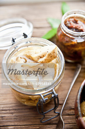 Preserved artichoke hearts and dried tomatoes in jars