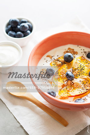 Yoghurt with peaches, blueberries, whole-grain flakes and chia seeds in a muesli bowl Yoghurt with peaches, blueberries, whole-grain flakes and chia seeds in a muesli bowl
