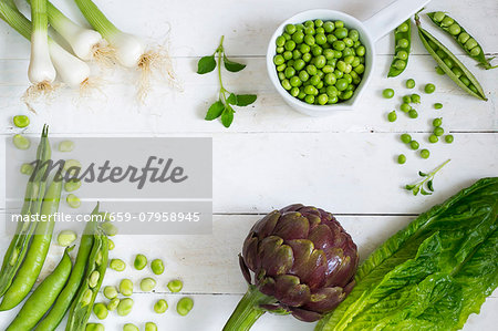 An arrangement of vegetables featuring a large artichoke and peas An arrangement of vegetables featuring a large artichoke and peas