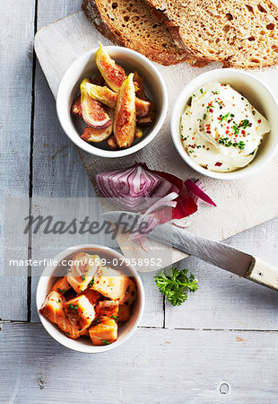 Salmon, slices of bread, cream cheese with herbs, figs and onions on a chopping board