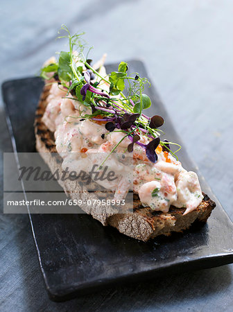 An open sandwich topped with prawn salad