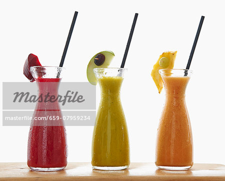 Three different smoothies in carafes Three different smoothies in carafes