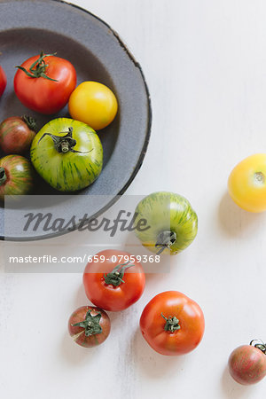 Various tomatoes on a plate and next to it Various tomatoes on a plate and next to it