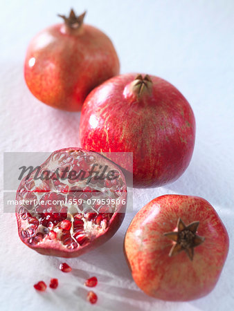 Three whole pomegranates and a halved one