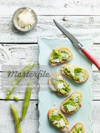 Crostini topped with fava beans and Parmesan cheese