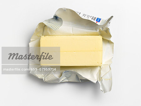 An unwrapped pat of butter on its wrapper An unwrapped pat of butter on its wrapper