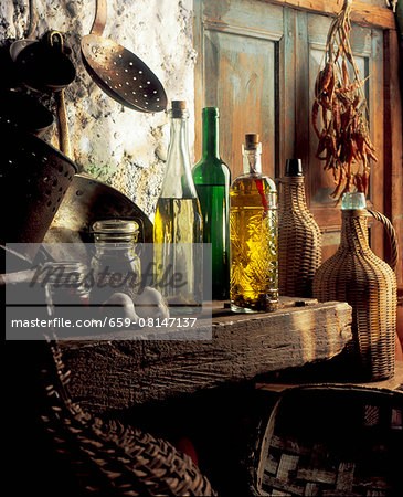 Bottles of oils, copper pots, jugs and spices in a rustic kitchen