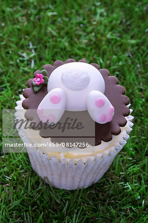An Easter bunny cupcake on a grass surface