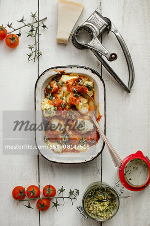 Shell pasta with a ricotta filling and puttanesca sauce, basil pesto, Parmesan cheese, a cheese grater and cherry tomatoes