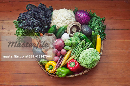 A basket of vegetables on a wooden surface A basket of vegetables on a wooden surface