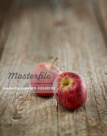 Two red apples on a wooden surface