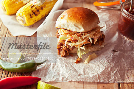 A pulled pork slider with apple coleslaw and grilled corn cobs (USA)